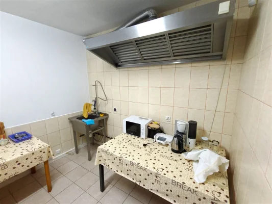 Aneks kuchenny Pensjonatu Nadmorskiego w Rewalu ze zlewem, okapem, mikrofalówką i ekspresem do kawy na stole z obrusem.